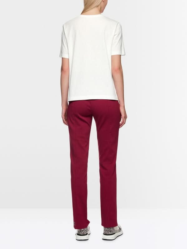 Vue arrière d'un mannequin portant un T-shirt à paillettes blanc avec un pantalon rouge, soulignant un style décontracté et moderne.