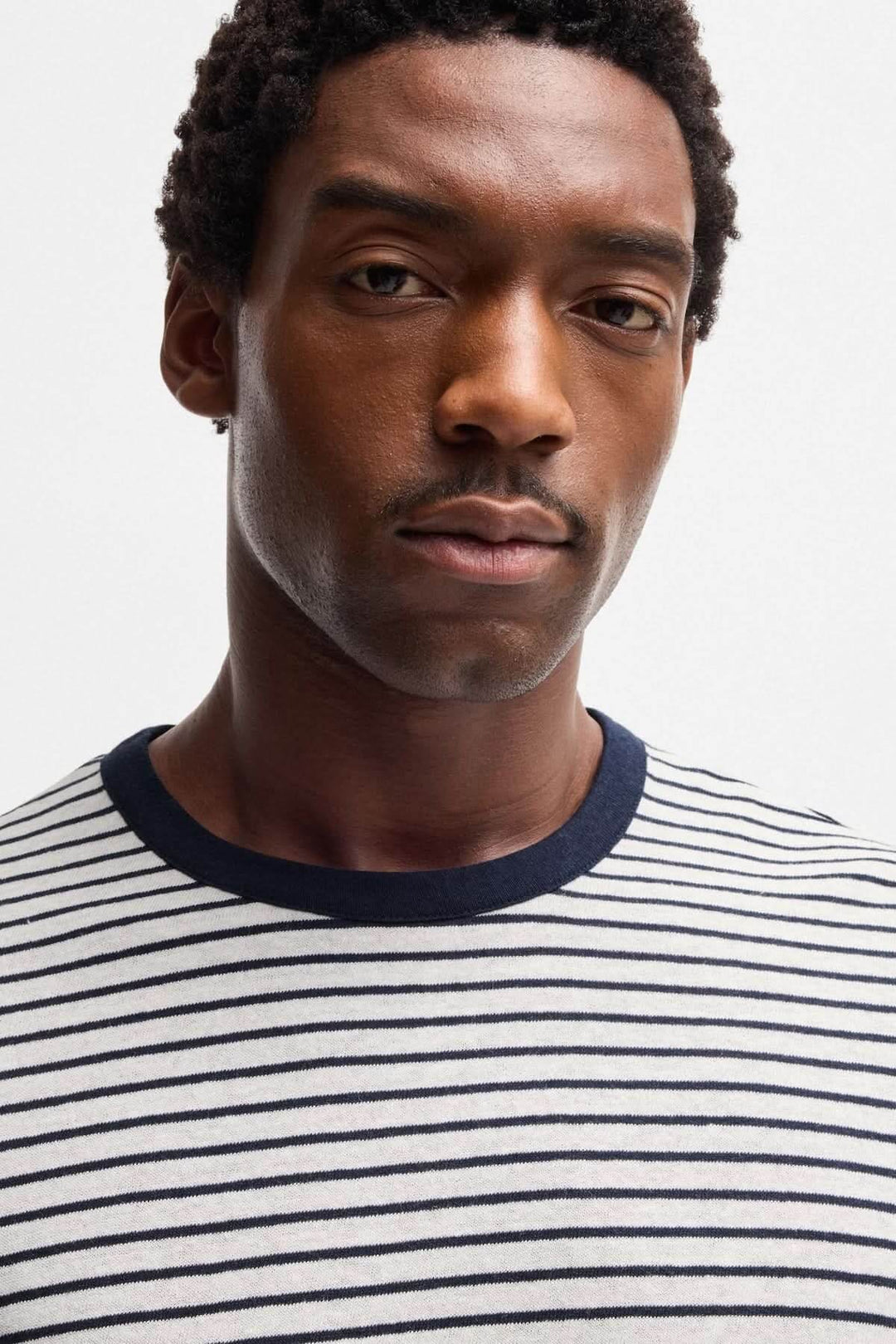 Homme portant un t-shirt rayé à col contrastant, élégant et décontracté, parfait pour un look estival.