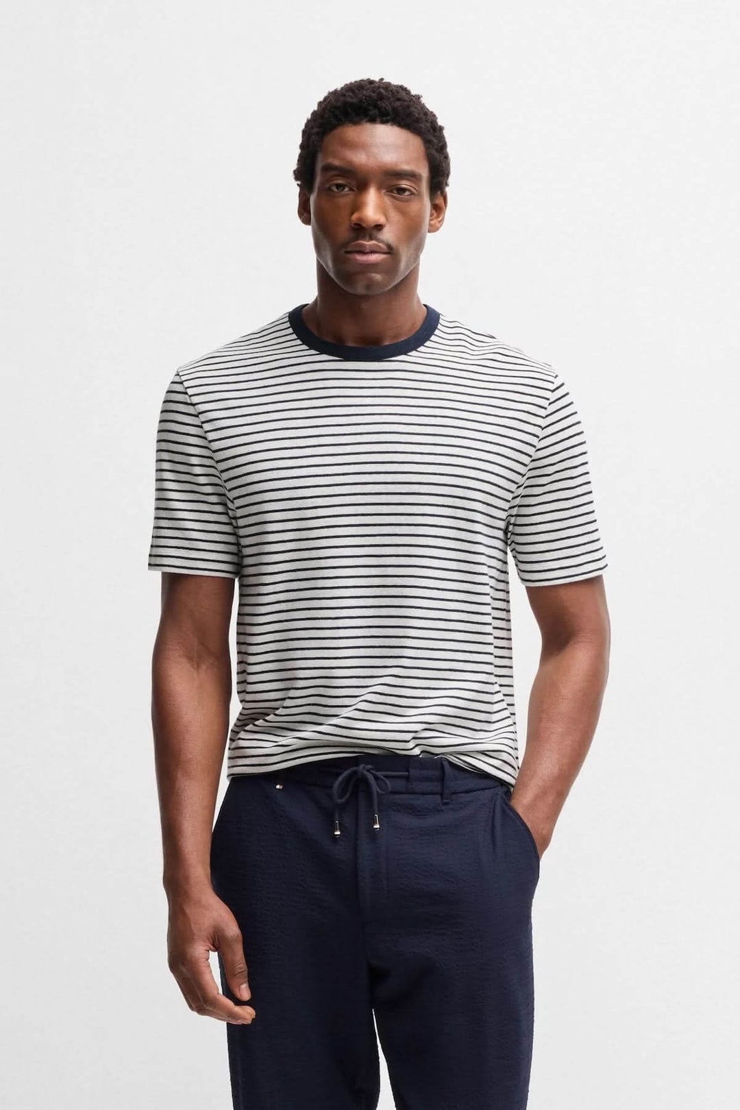 Homme portant un t-shirt rayé à col contrastant, avec un look décontracté et moderne.