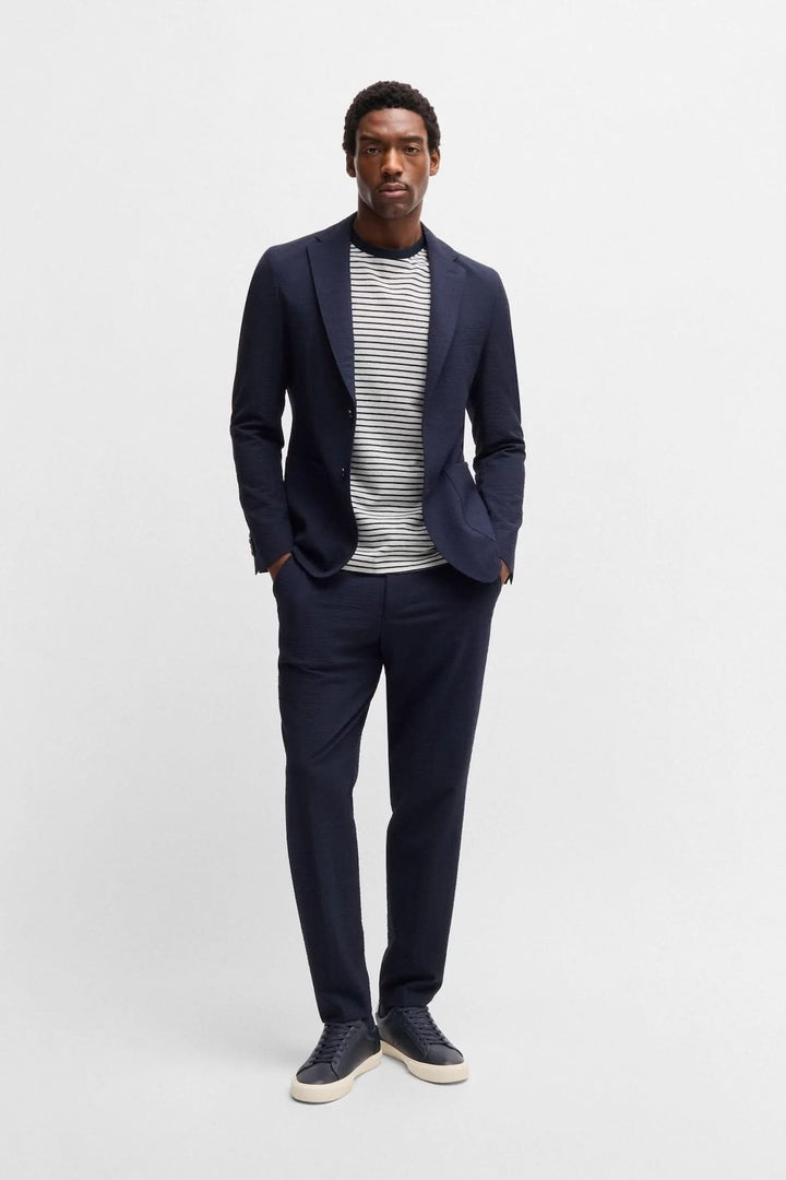 Homme en costume navy avec t-shirt rayé, look moderne et décontracté.