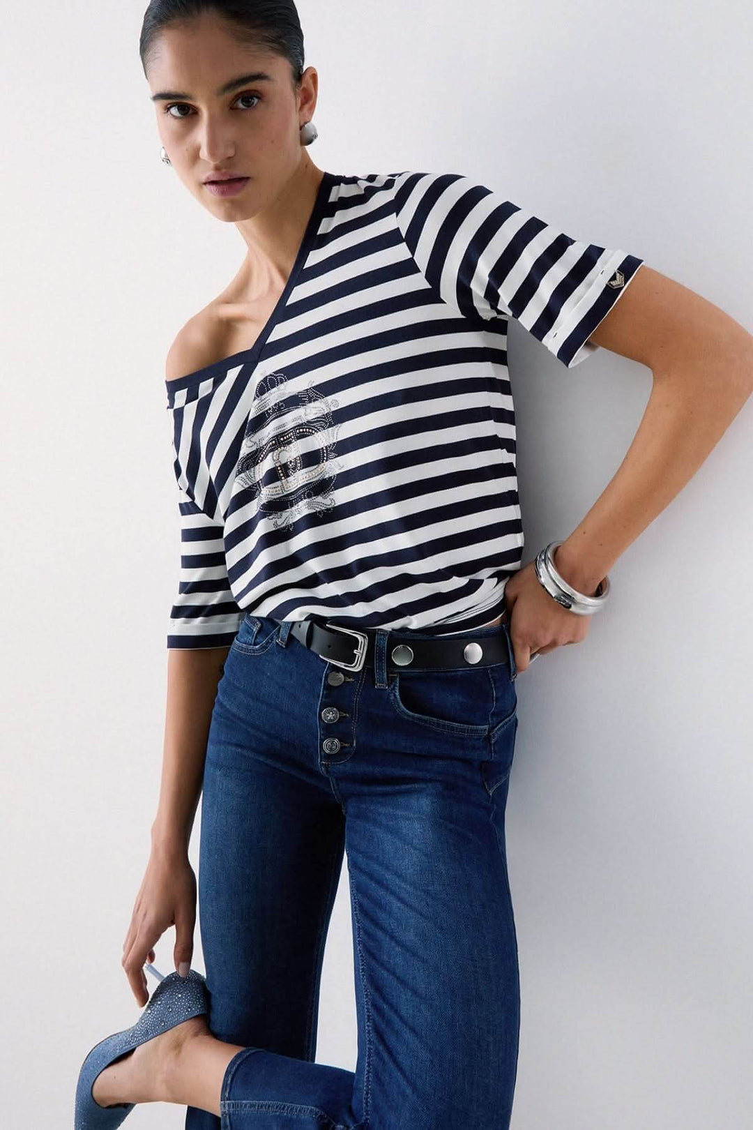 Femme portant un t-shirt rayé col en V avec motif décoratif élégant et moderne.