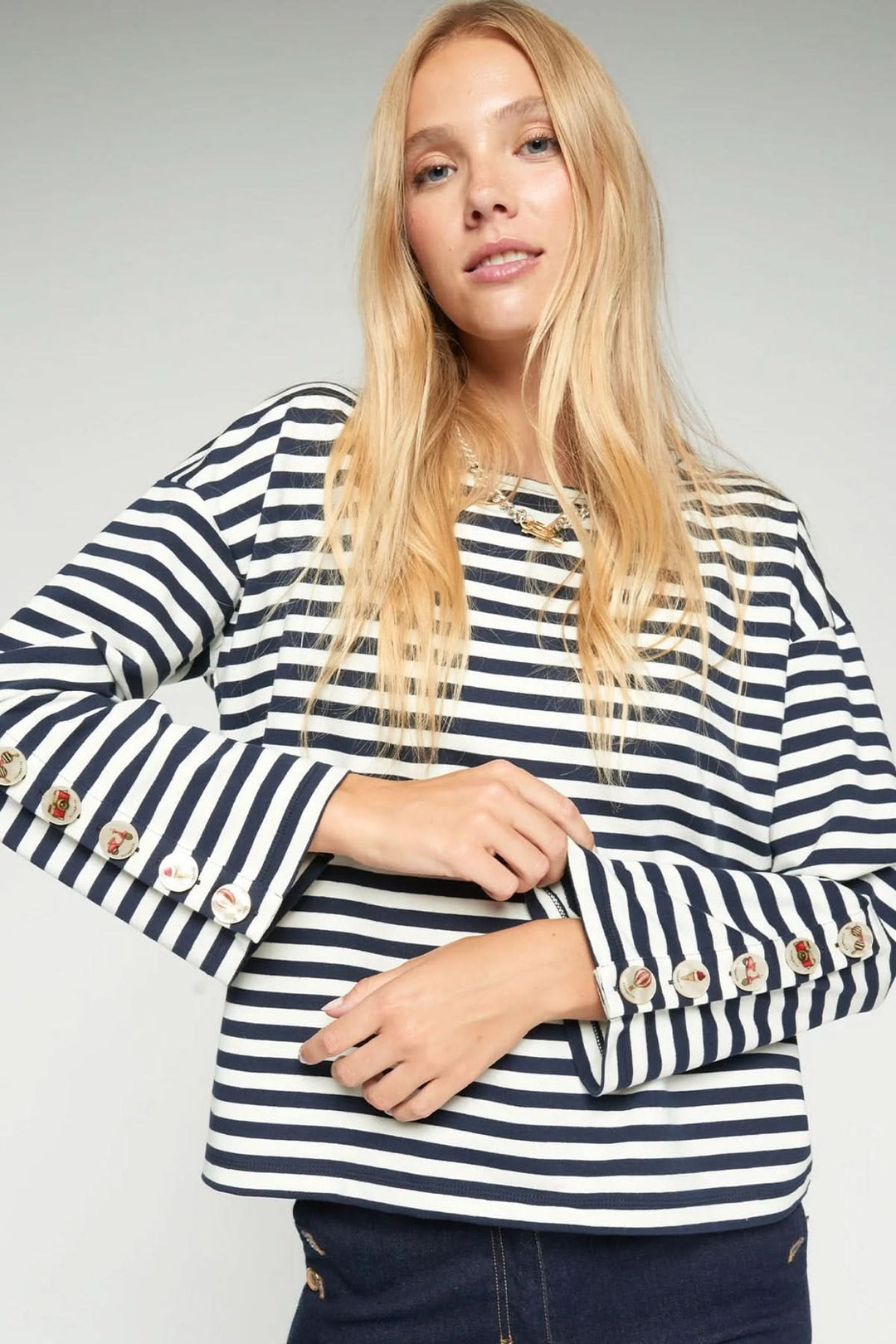 Femme portant un T-shirt rayé à manches longues avec boutons décoratifs, style élégant et décontracté.