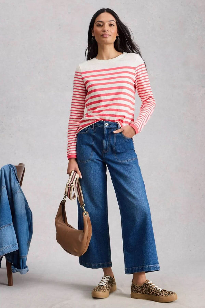 Femme portant un T-shirt rayé à manches longues avec jean large et sac marron, tenue décontractée et chic.