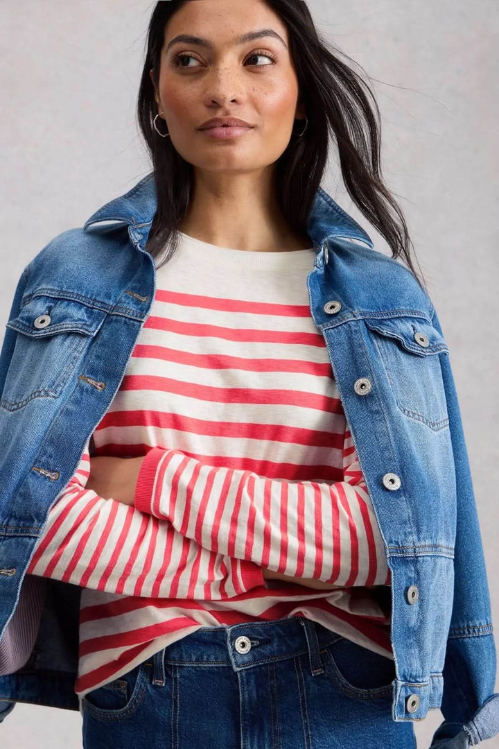 Femme portant un T-shirt rayé à manches longues avec une veste en jean, style décontracté et soigné.