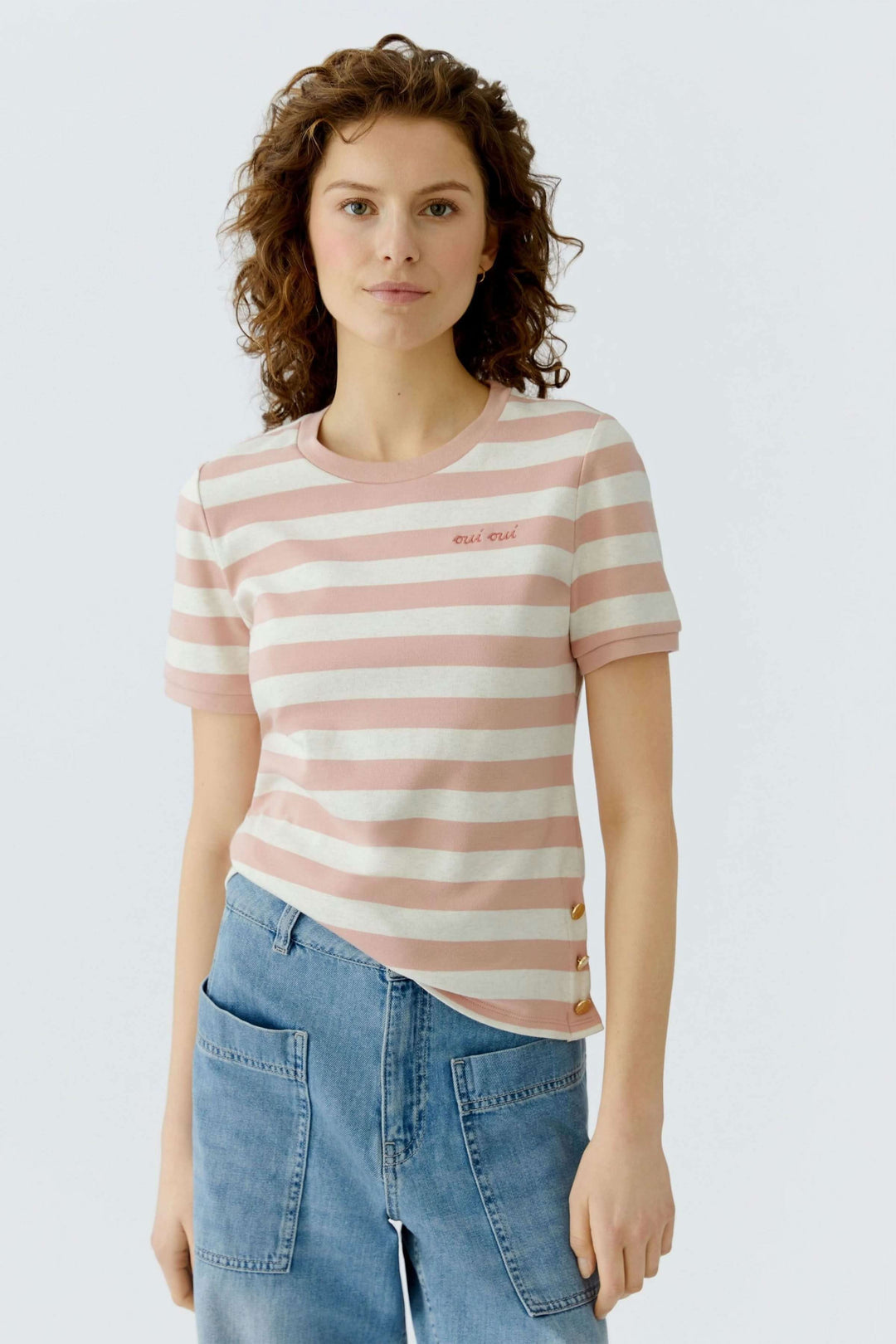 Femme portant un t-shirt à rayures avec détails décoratifs, coupe droite et manches courtes, s'intégrant facilement à une tenue quotidienne.