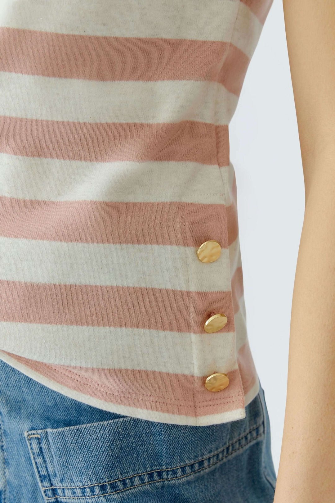 Gros plan sur le T-shirt à rayures avec détails décoratifs en boutons dorés sur le côté, coupe droite et design moderne.