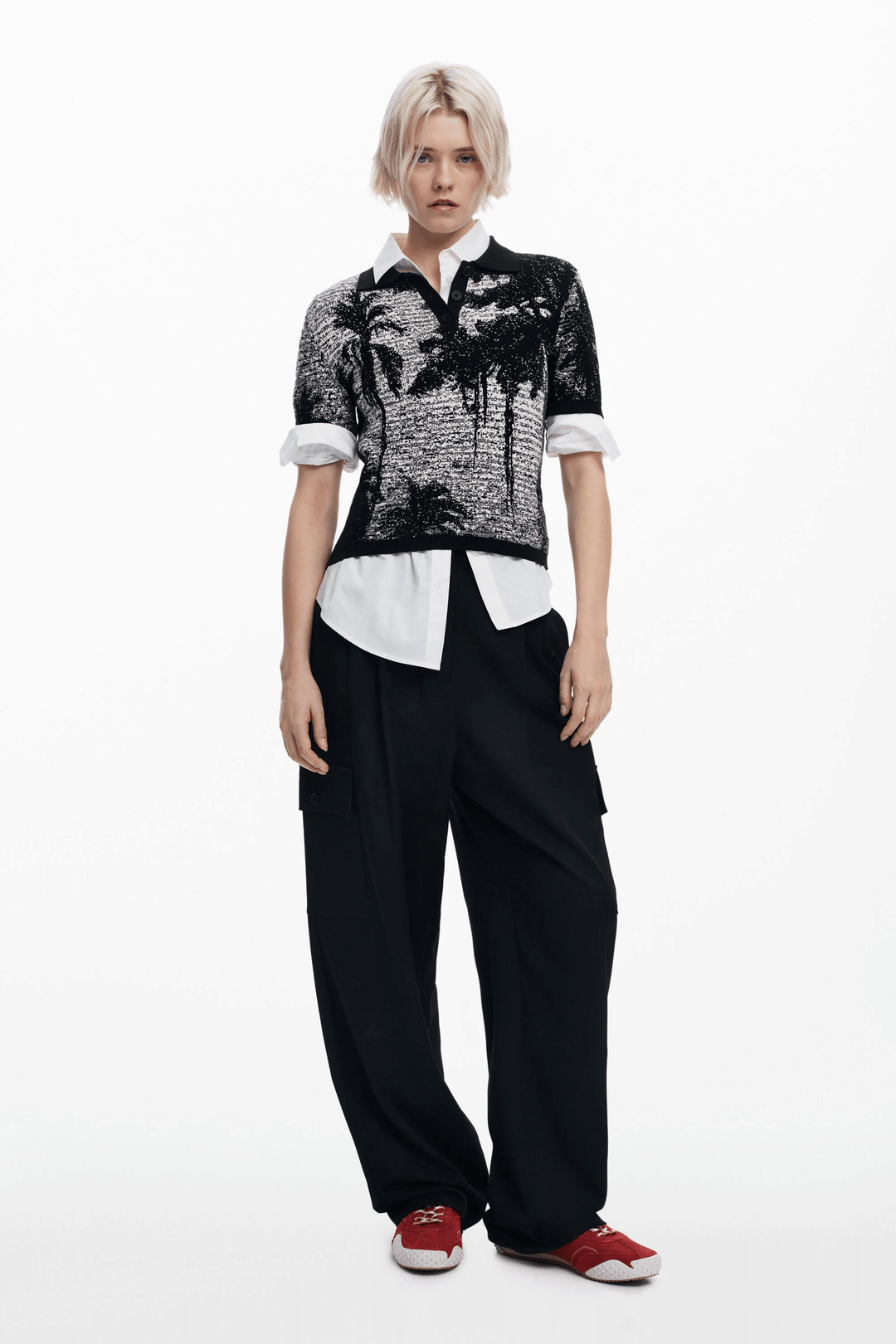 T-shirt style polo à manches courtes avec imprimé paysage, porté avec un pantalon ample pour un look estival.
