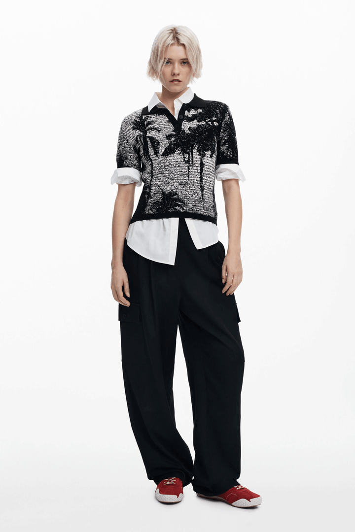 T-shirt style polo à manches courtes avec imprimé paysage, porté avec un pantalon ample pour un look estival.