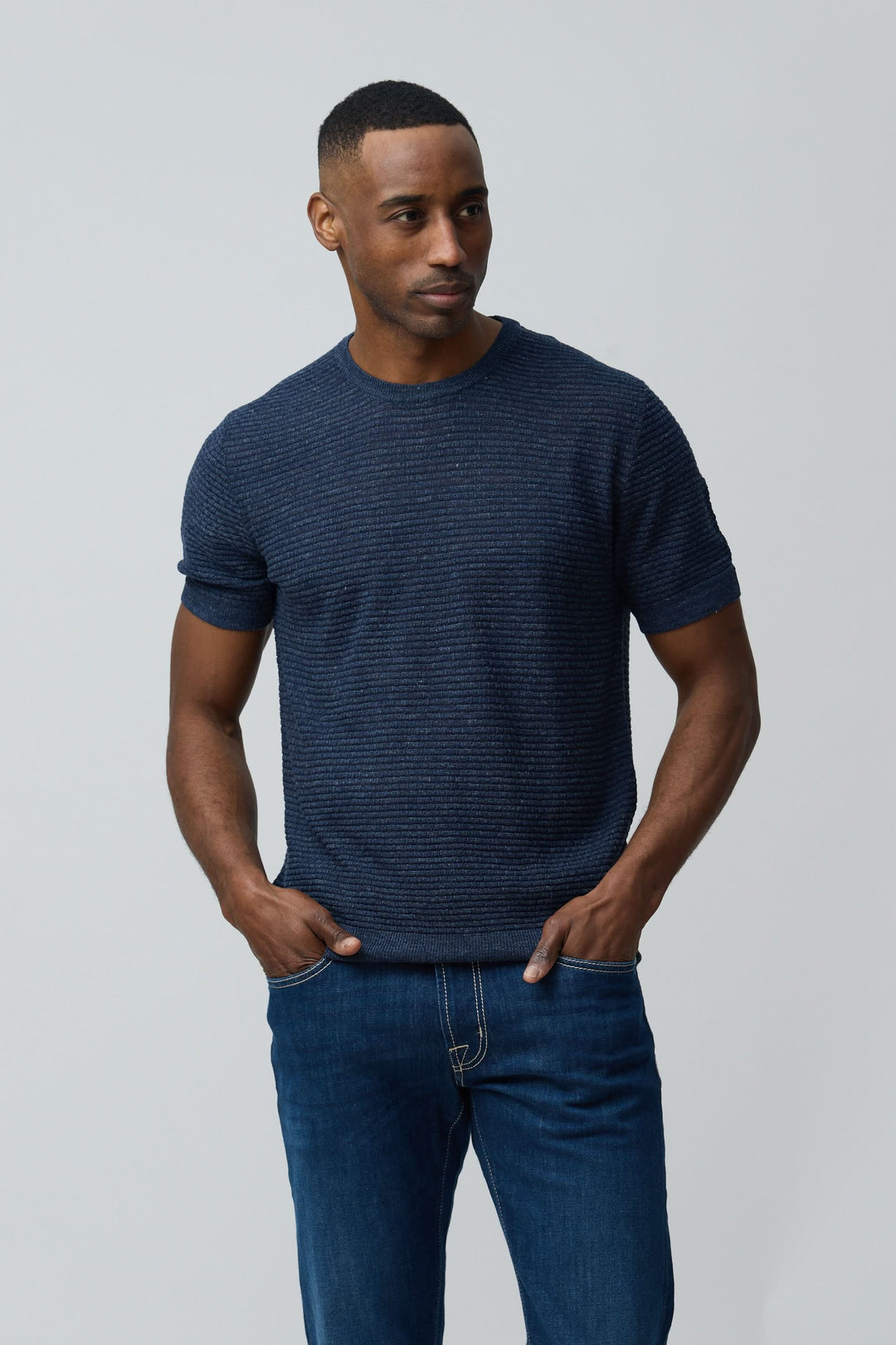 Homme portant un T-shirt texturé en lin et soie bleu marine, coupe ajustée, avec manches courtes. Décris moi le produit en français.