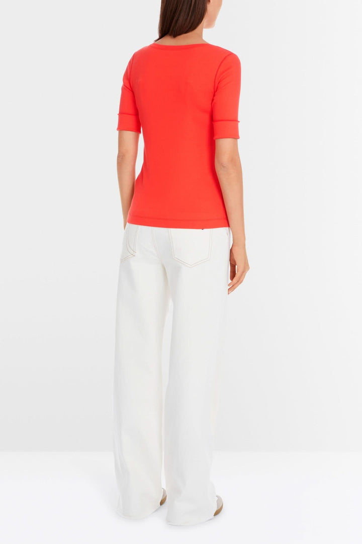 Back view of a fitted stretch cotton T-shirt with 3/4 sleeves in bright coral, paired with white wide-leg pants.