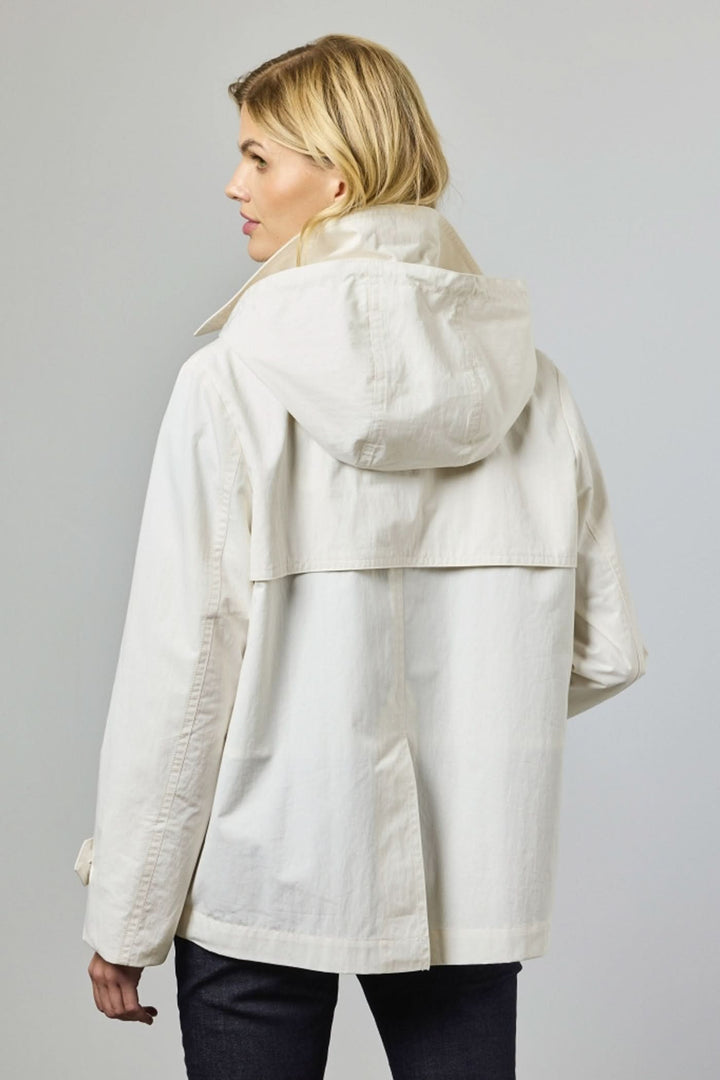 Femme portant un trench court croisé blanc avec capuche, vue de dos. Style moderne et épuré, parfait pour superpositions élégantes.