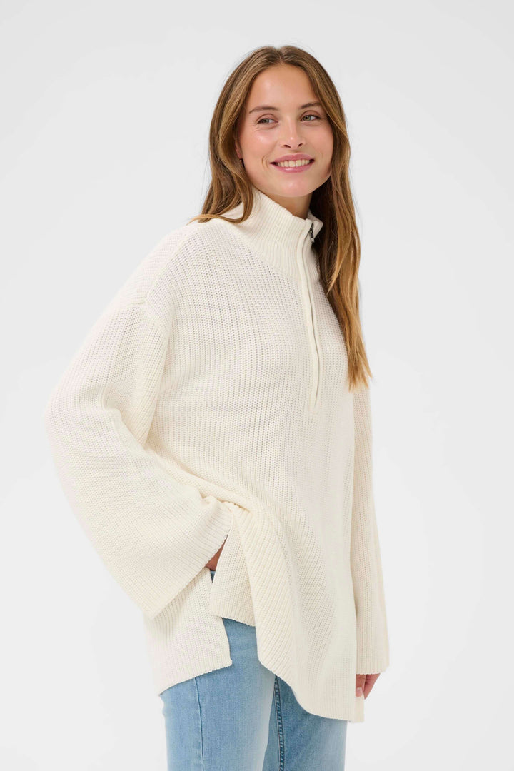 Tricot Pietra ample blanc avec col montant zippé, style décontracté et texture en maille, porté par une femme, sur fond blanc.