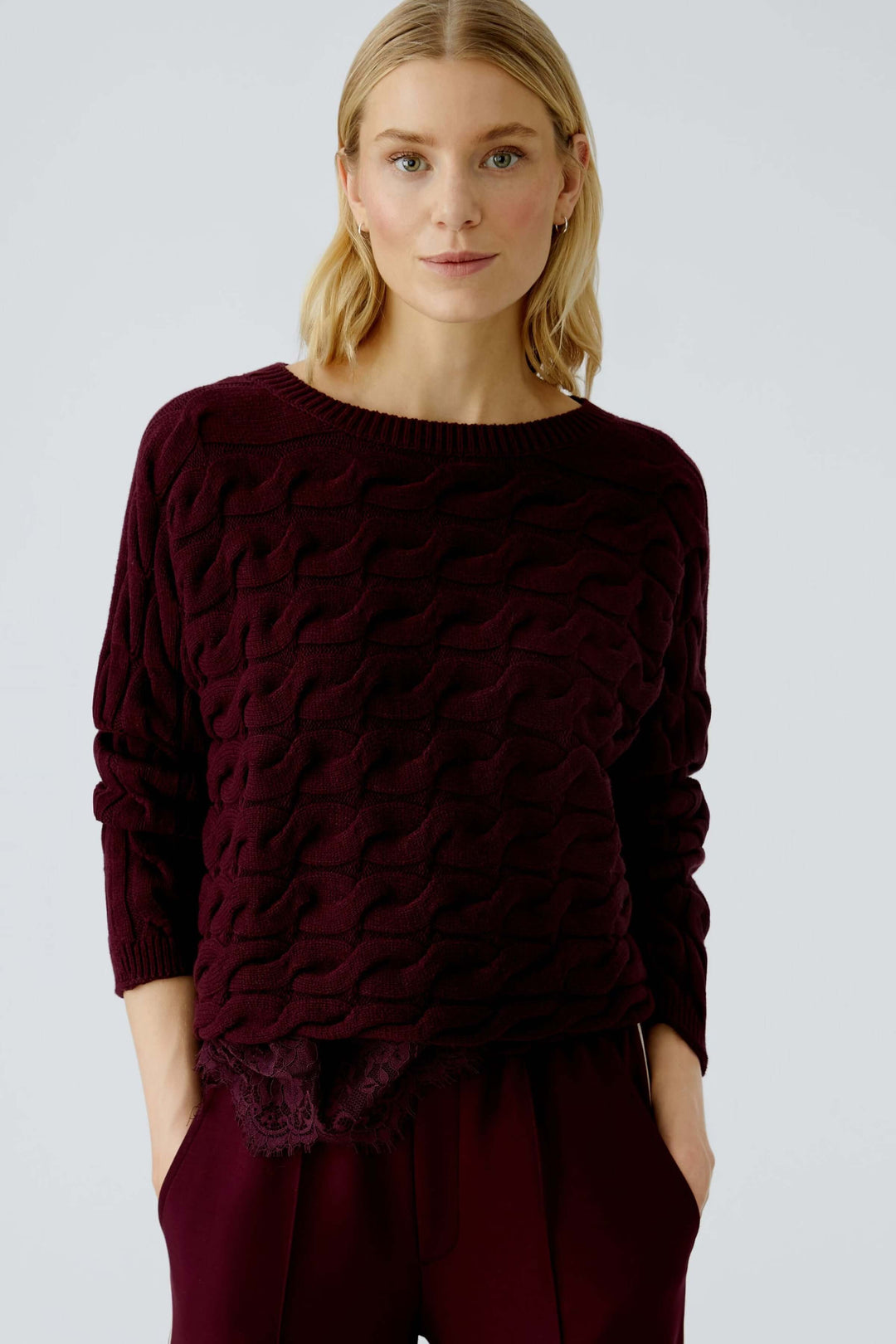 Femme portant un Tricot Sirah torsadé en coton, coupe carrée, col bateau. Moderne et élégant, idéal pour le confort et le raffinement.