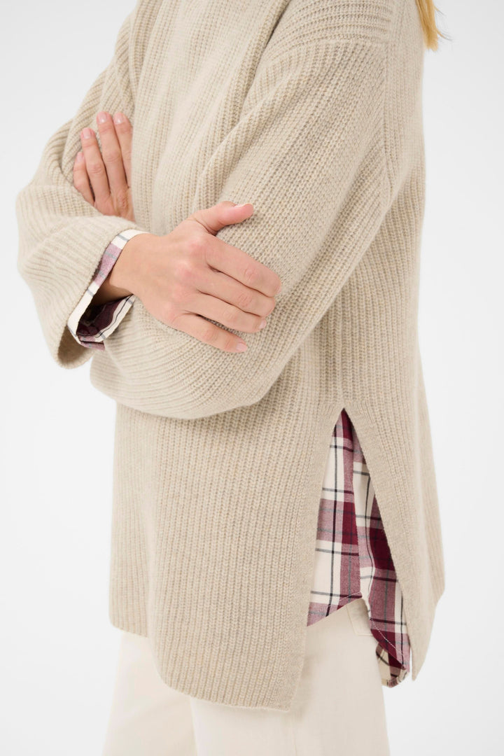 Tricot Sofiya à col montant, coupe ample, tricot côtelé doux, avec détails fendus, parfait pour une tenue moderne et équilibrée.