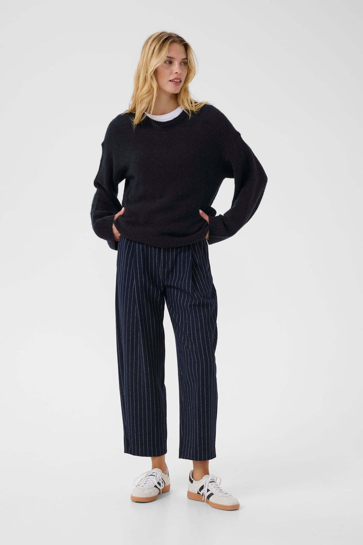 Femme portant Tricot Spence noir avec manches longues, col rond, idéal pour un look décontracté et chic.