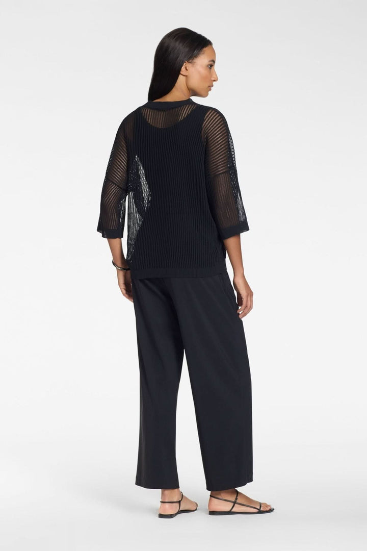Femme portant un tricot ajouré en maille légère manches 3/4, vue de dos, avec encolure ronde et texture fluide pour un look moderne.