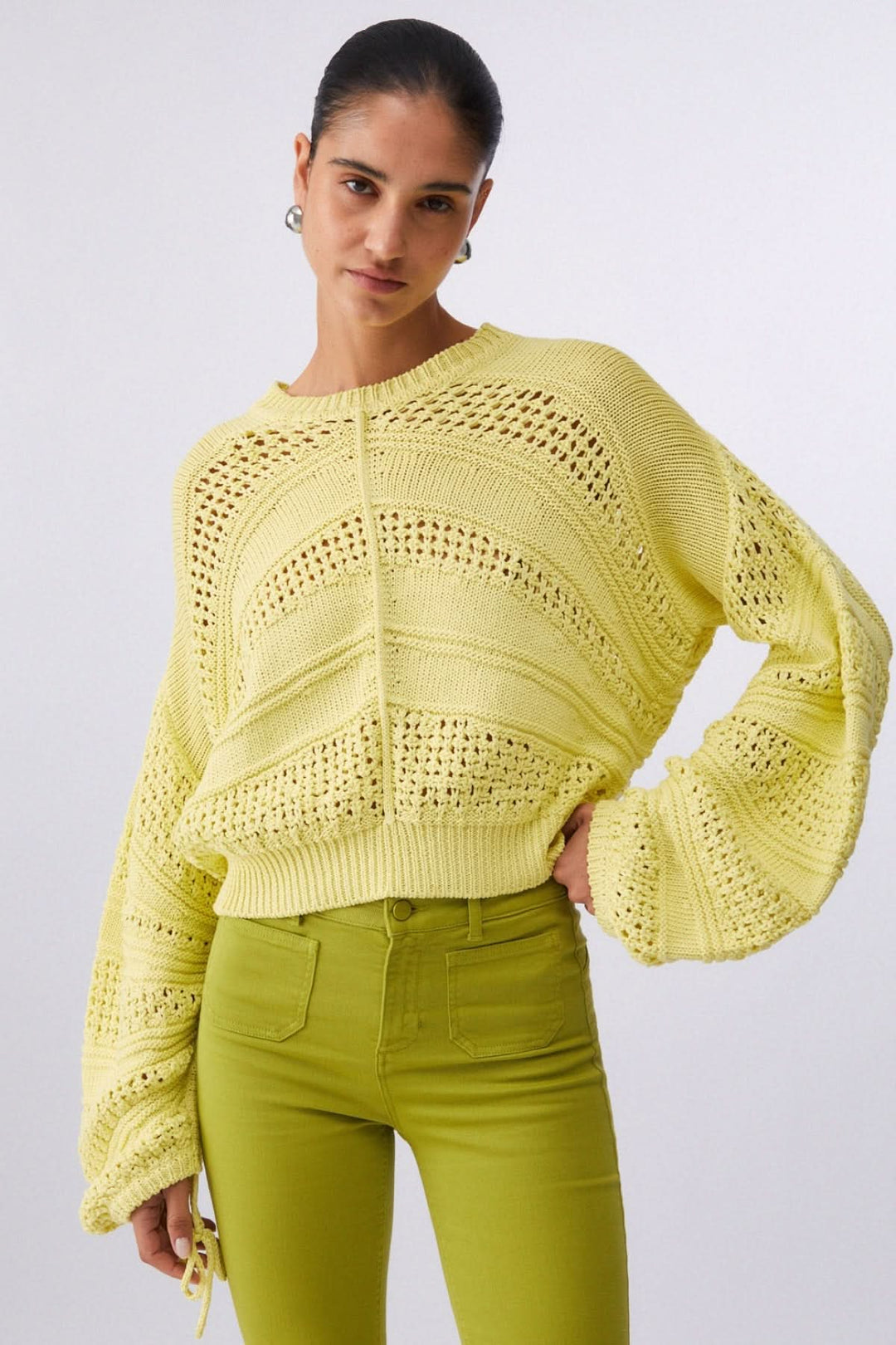 Tricot ajouré à manches longues, style moderne avec maille texturée jaune, idéal pour mi-saison, modèle féminin portant le tricot.
