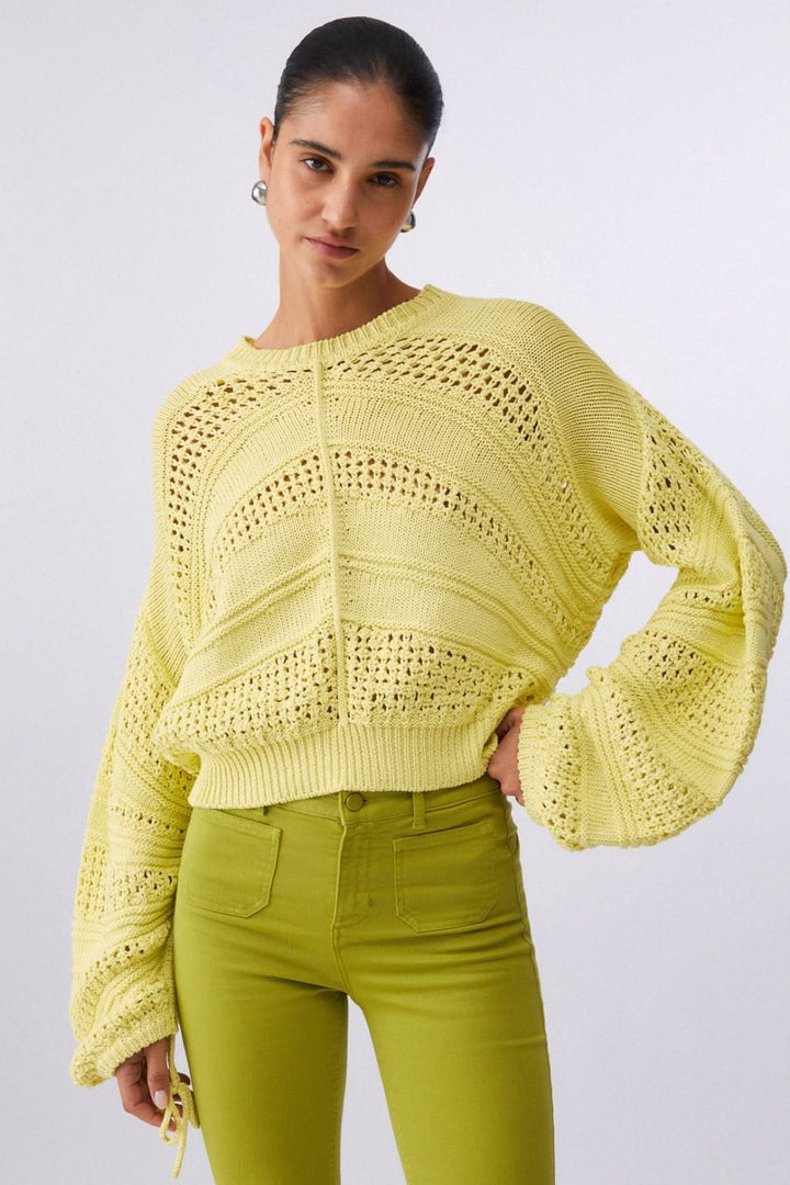 Tricot ajouré à manches longues, style moderne avec maille texturée jaune, idéal pour mi-saison, modèle féminin portant le tricot.