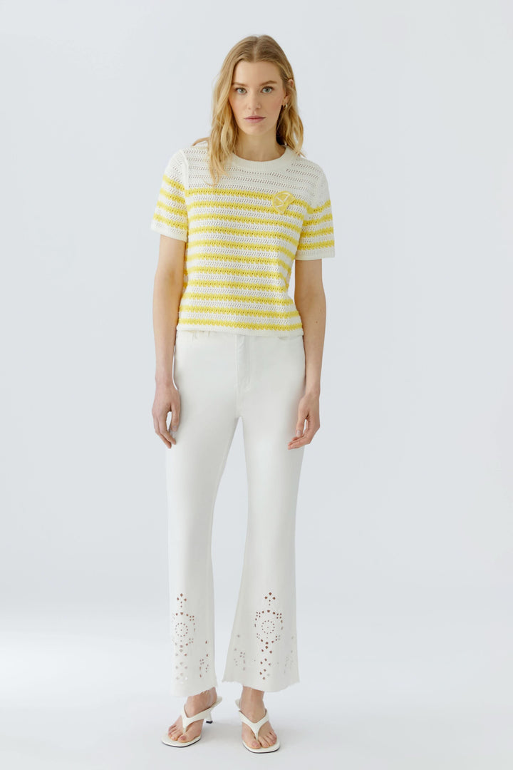 Modèle portant un tricot ajouré à rayures manches courtes jaune et blanc, coupe ajustée, moderne et féminin.