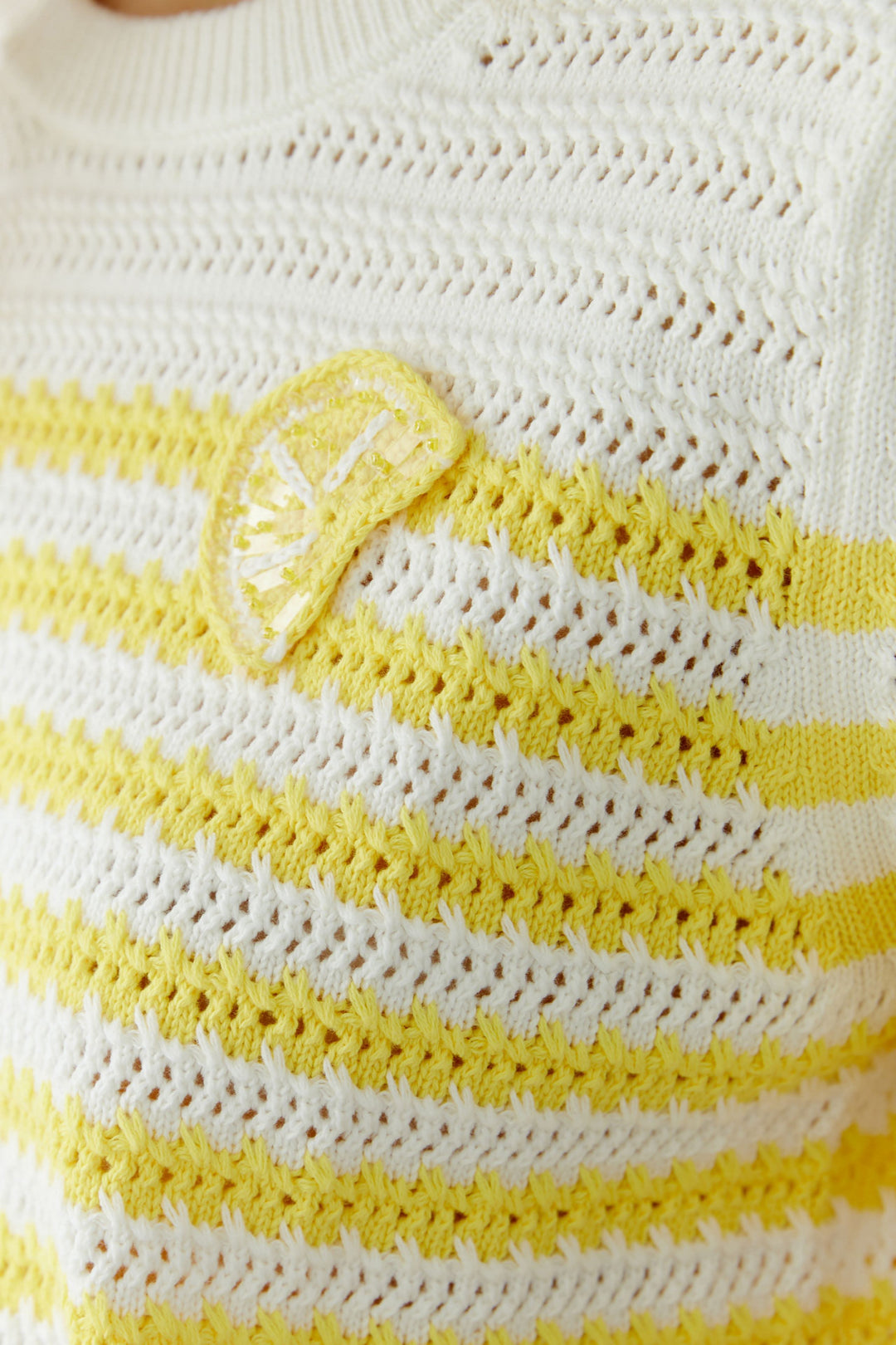 Tricot ajouré à rayures manches courtes avec motif structuré et détail distinctif à la poitrine jaune et blanc.