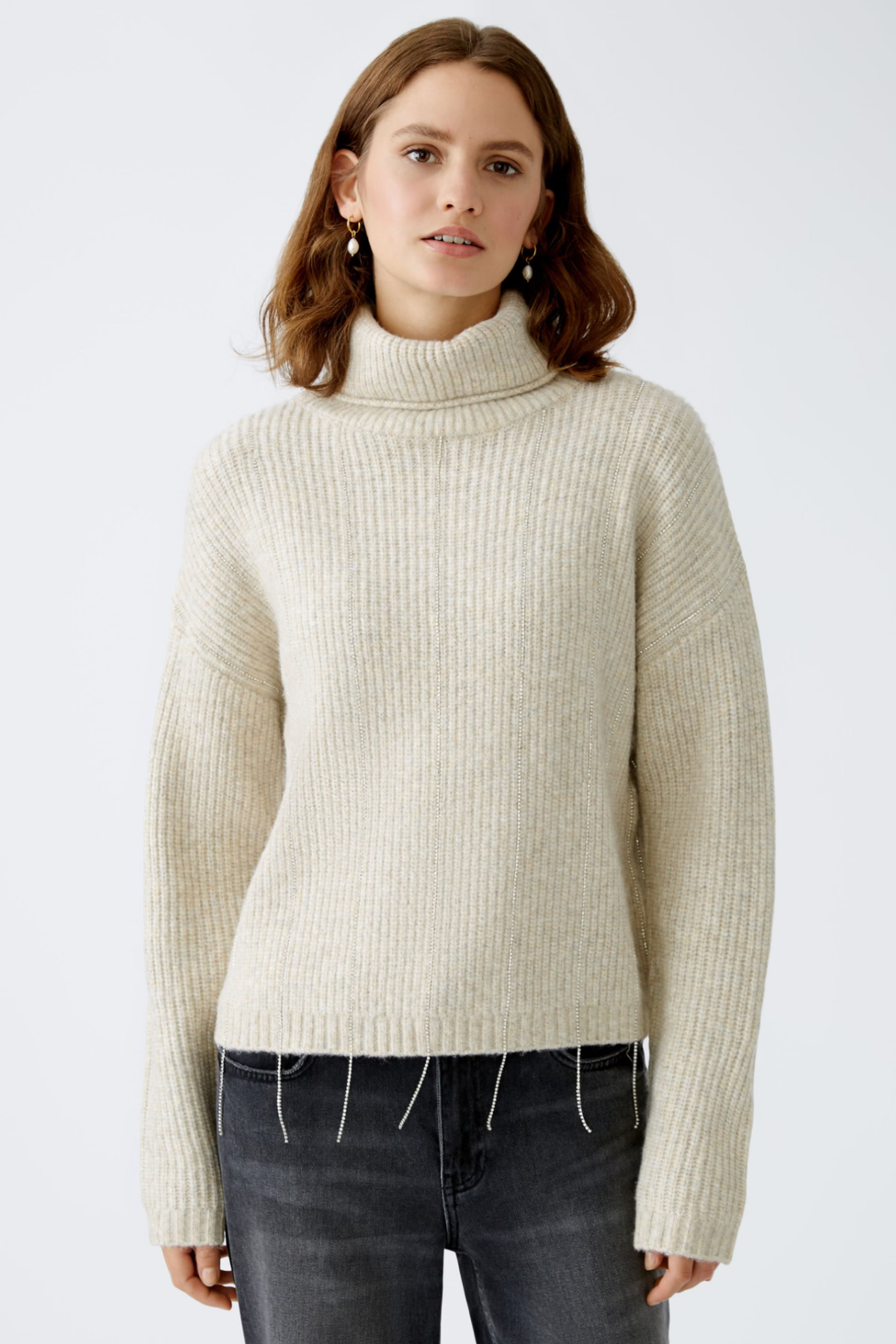 Tricot beige avec col roulé, maille côtelée et détails scintillants, style décontracté et moderne.