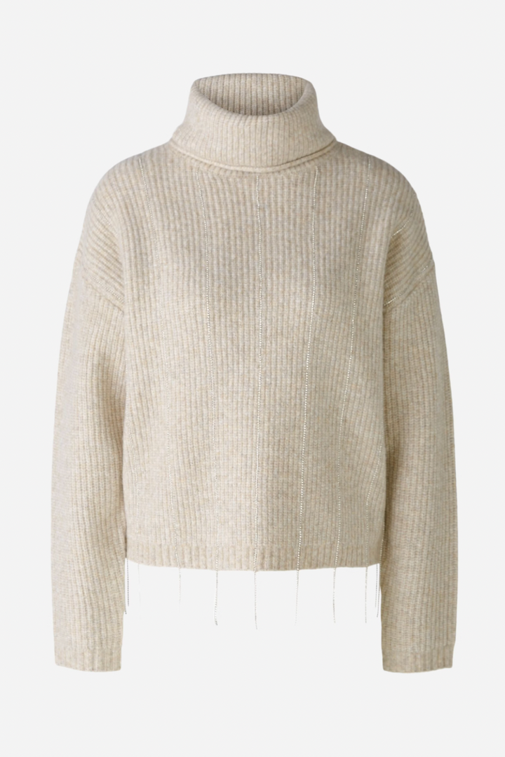 Tricot avec fils pailletés, col roulé, maille côtelée, et ourlet orné de rubans scintillants.
