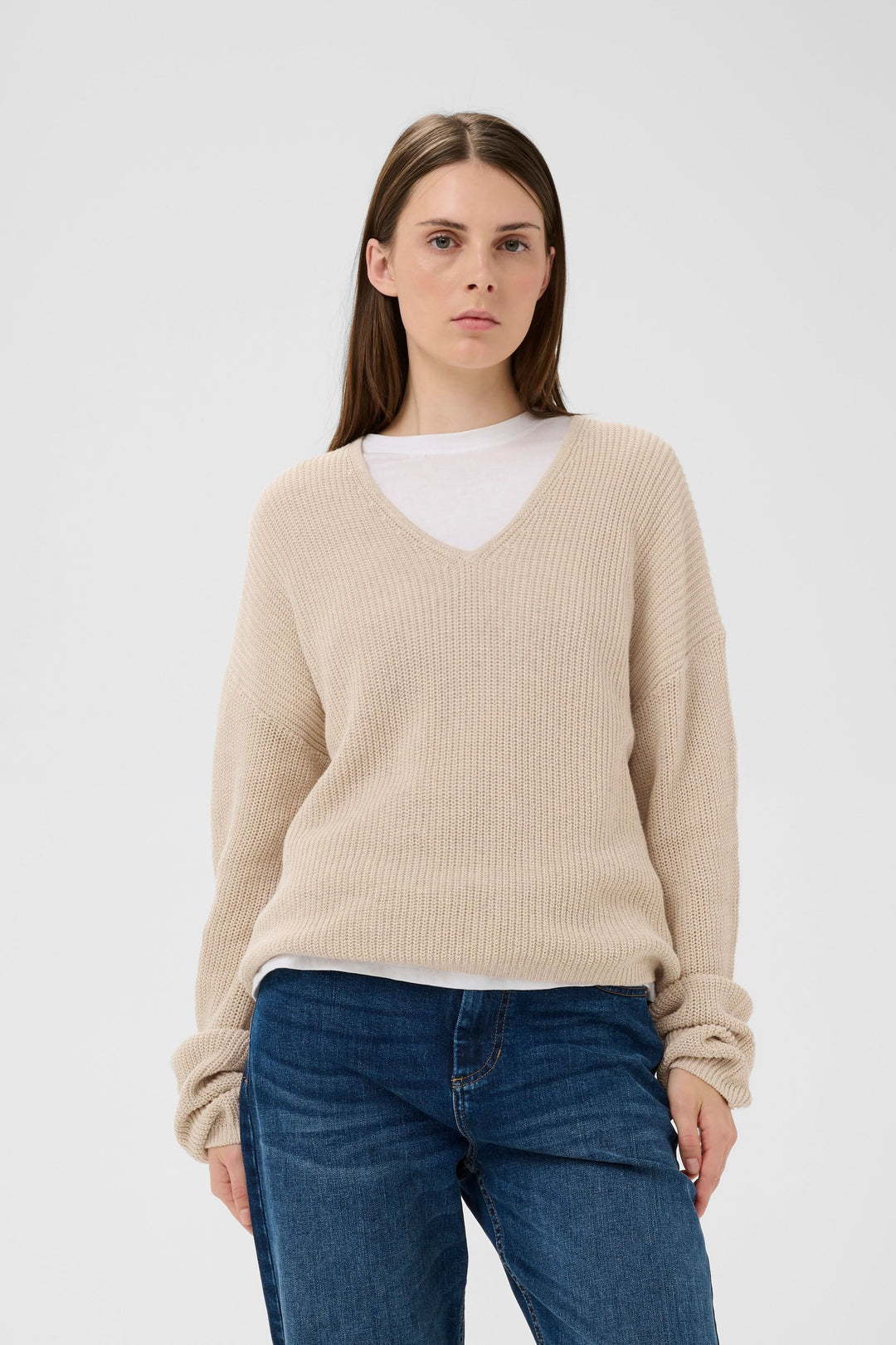 Tricot col V en maille, modèle décontracté avec maille texturée, porté sur un t-shirt blanc pour un look confortable et chic.