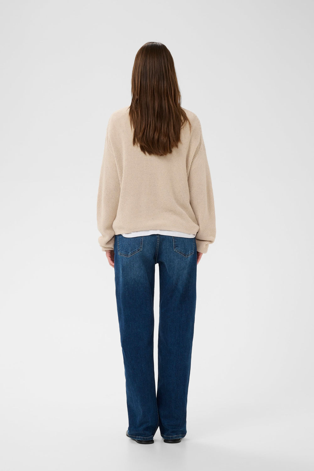 Vue arrière d'une personne portant un tricot col V en maille beige avec une silhouette décontractée, idéal pour le quotidien.