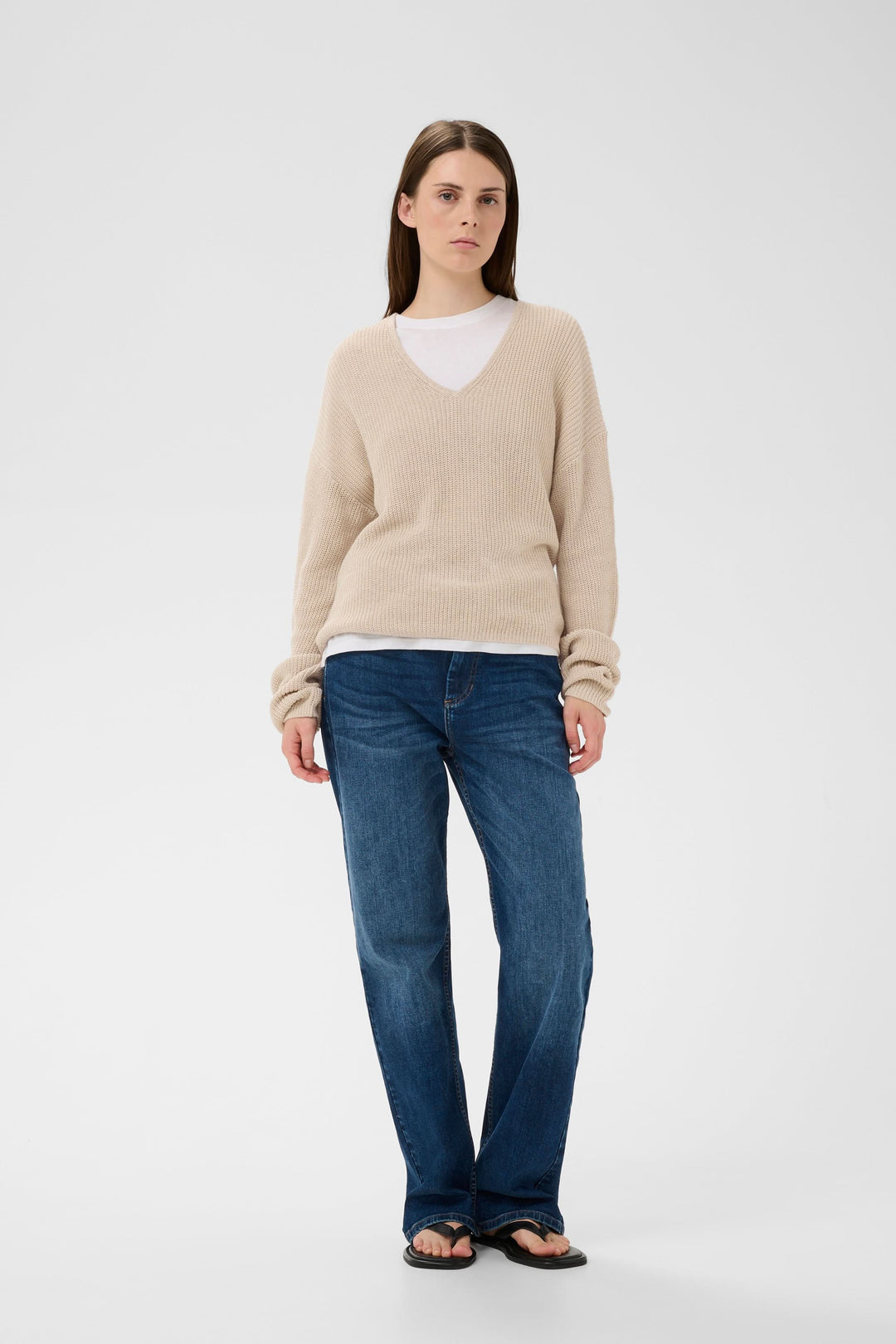 Tricot col V en maille texturée beige porté avec jean décontracté