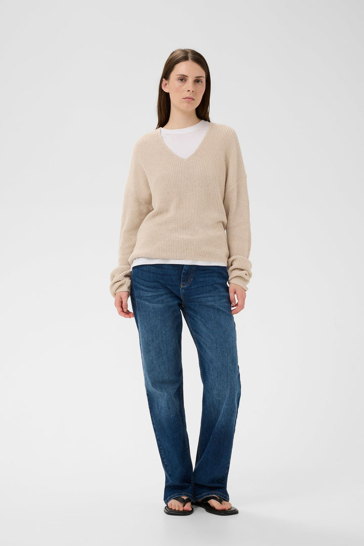 Tricot col V en maille texturée beige porté avec jean décontracté