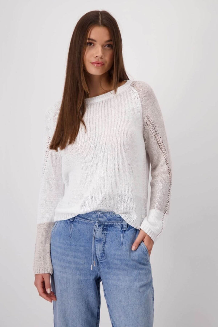 Model wearing a stylish white color block knit pullover paired with denim jeans.
