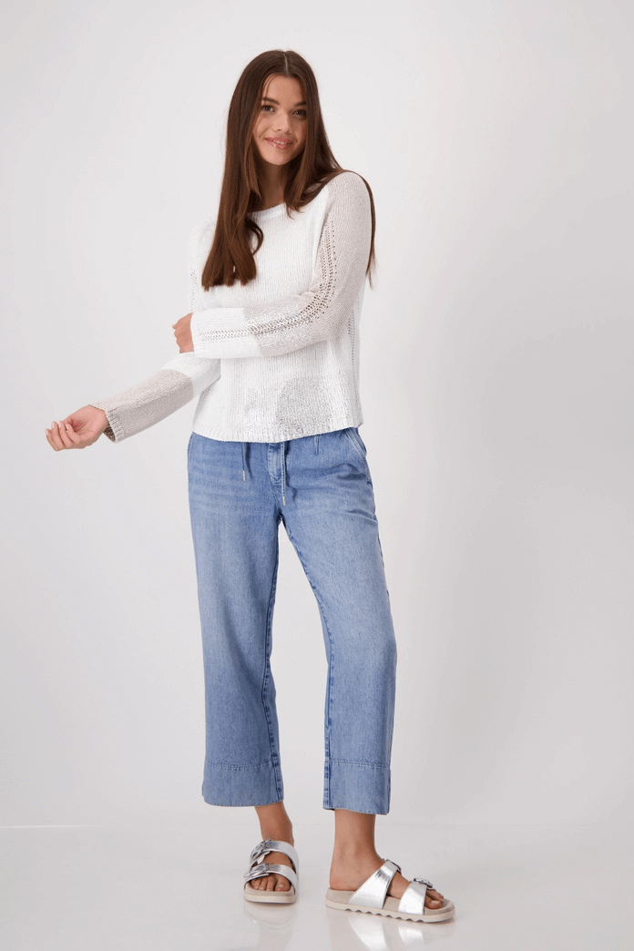 Woman wearing a stylish color block pullover tricot and denim pants, showcasing a modern design and metallic finish.