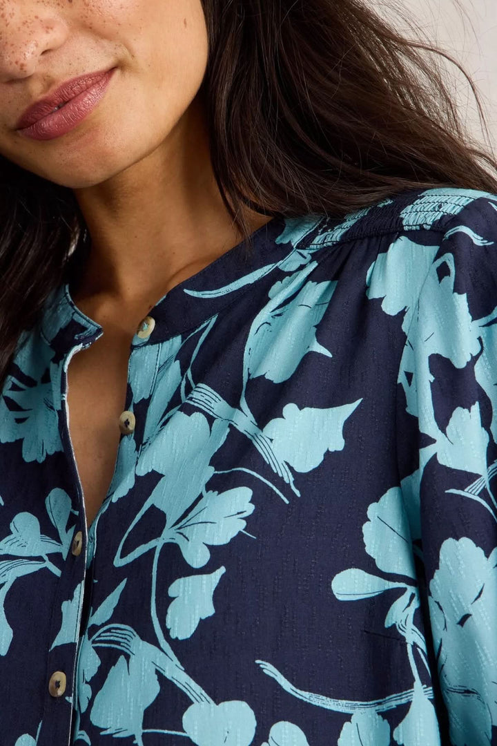 Close-up of model wearing Tunique Amy with bold botanical print in blue and navy, showcasing relaxed style.