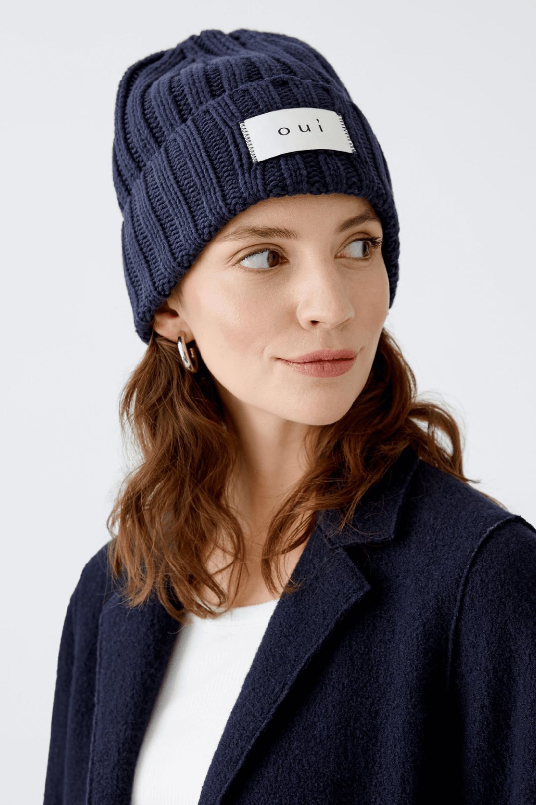 Femme portant une tuque en tricot bleu marine avec le logo « oui », style urbain et confortable.