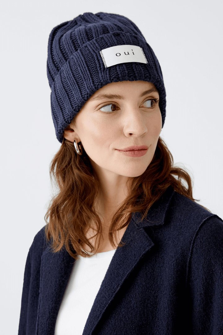 Femme portant une tuque en tricot bleu marine avec le logo « oui », style urbain et confortable.