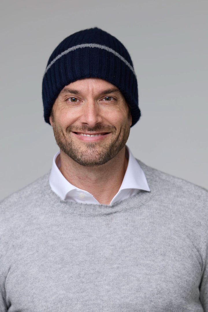Homme portant une tuque en tricot côtelé bleu marine avec détail contrastant gris, idéale pour l'hiver.