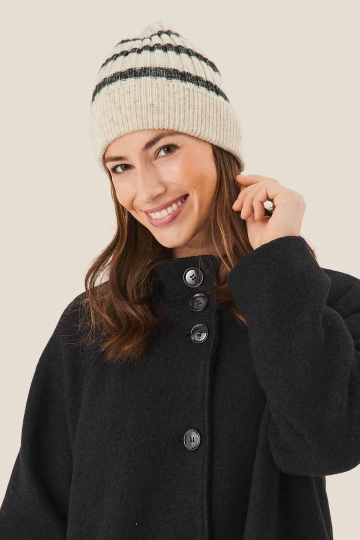 Femme souriante portant un bonnet à rayures grises et blanches, assortie d&