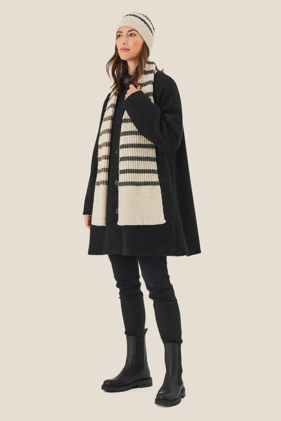 Femme portant une tuque lignée et une écharpe rayée, vêtue d&