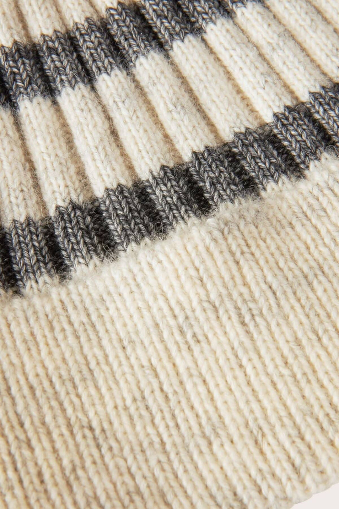 Gros plan sur un bonnet à rayures grises et crème, en tissu doux en laine et coton, parfait pour l&