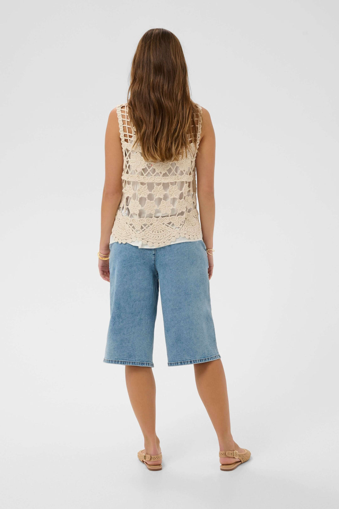 Modele portant une Veste Lotu sans manches en crochet, motif ajouré, vue arrière, tenue décontractée bohème chic pour l&