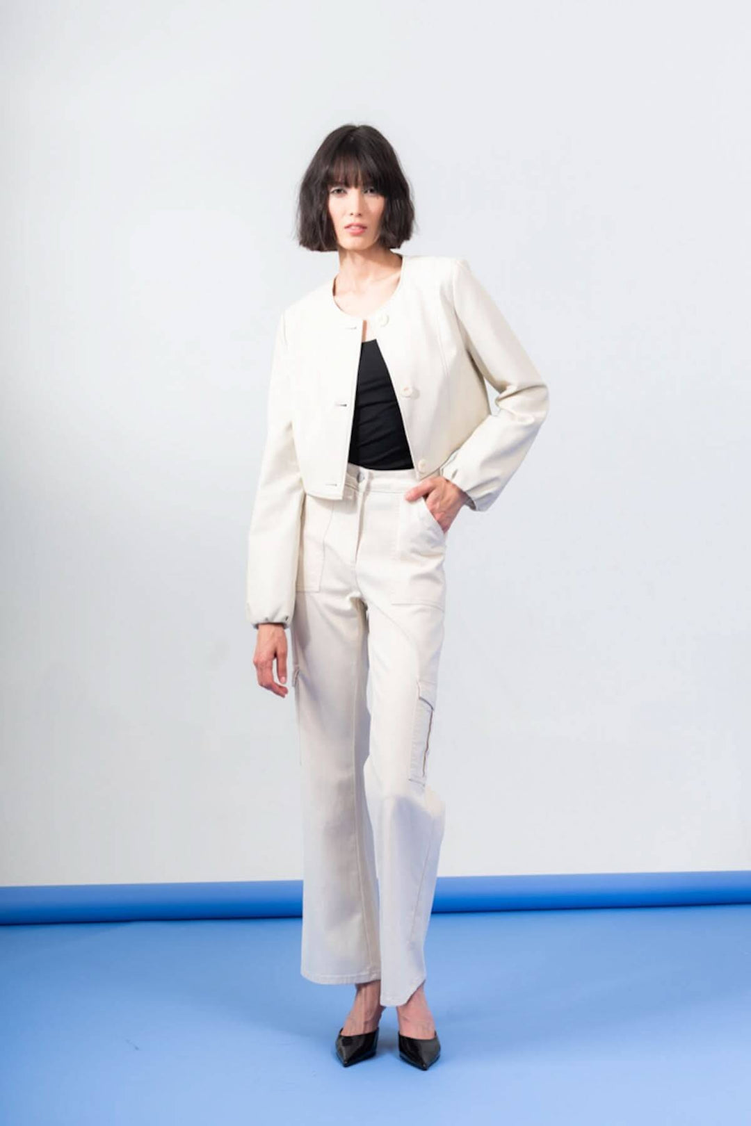 Modèle portant une veste péplum boutonnée beige et un pantalon assorti, mise en avant du style chic et élégant.