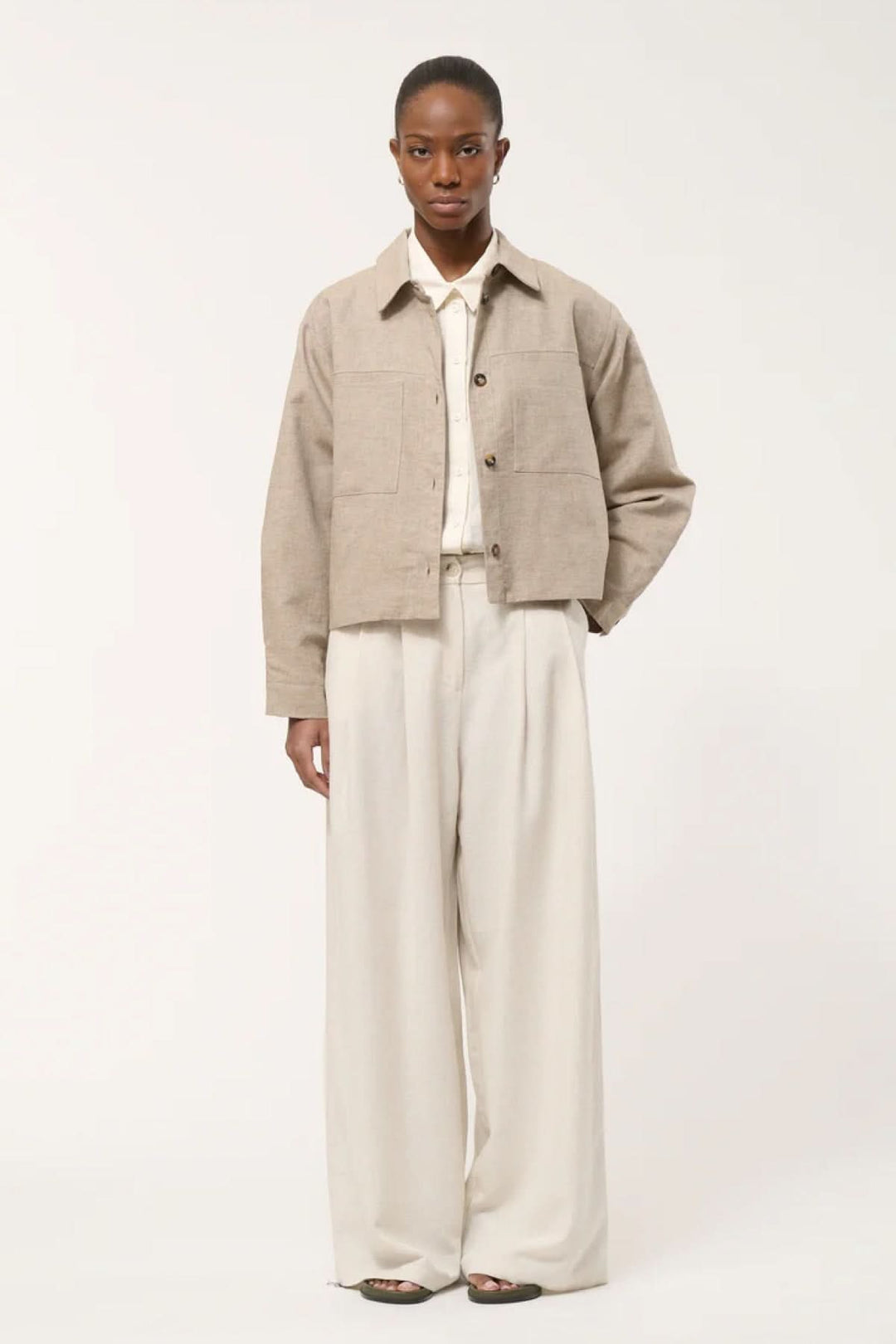 "Veste chemise courte en tissu naturel, coupe structurée courtes et élégante, avec poches plaquées et col chemise, vue de face."