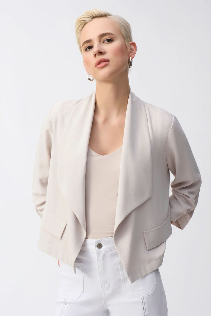 Veste col châle beige en crêpe, forme ouverte, manches longues, élégante et décontractée, portée par un mannequin.