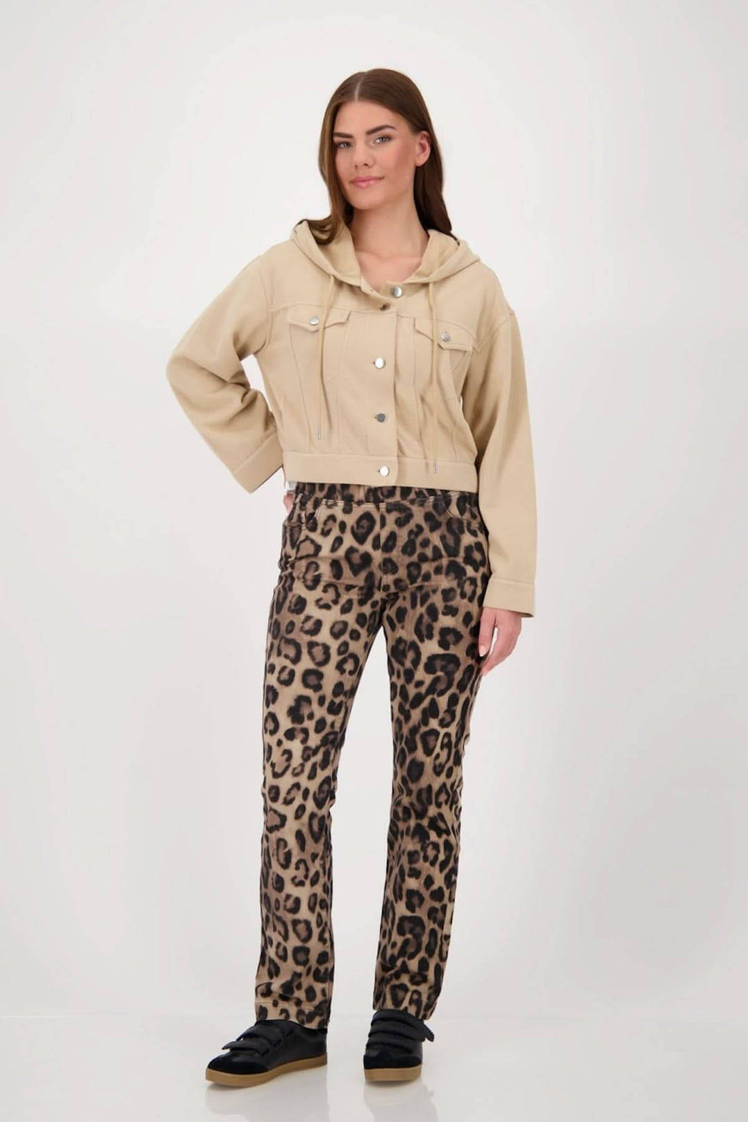 Modèle portant une veste courte à capuchon beige avec des poches, assortie à un pantalon léopard, style décontracté.