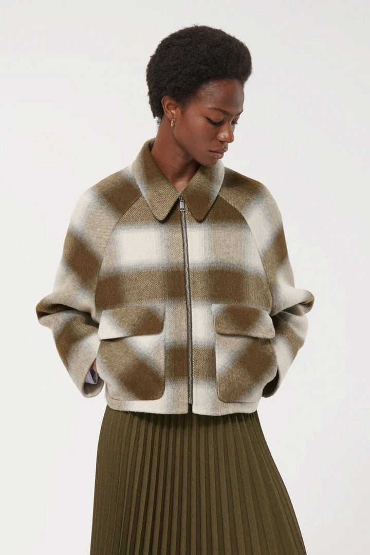 Veste courte à carreaux pour un style moderne avec poches à rabat, parfaite pour l'automne, portée par une femme.