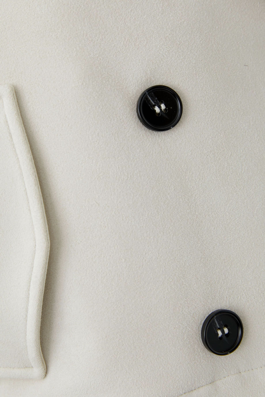 Détail de la Veste courte croisée à col tailleur avec boutons noirs et texture en tissu élégant.