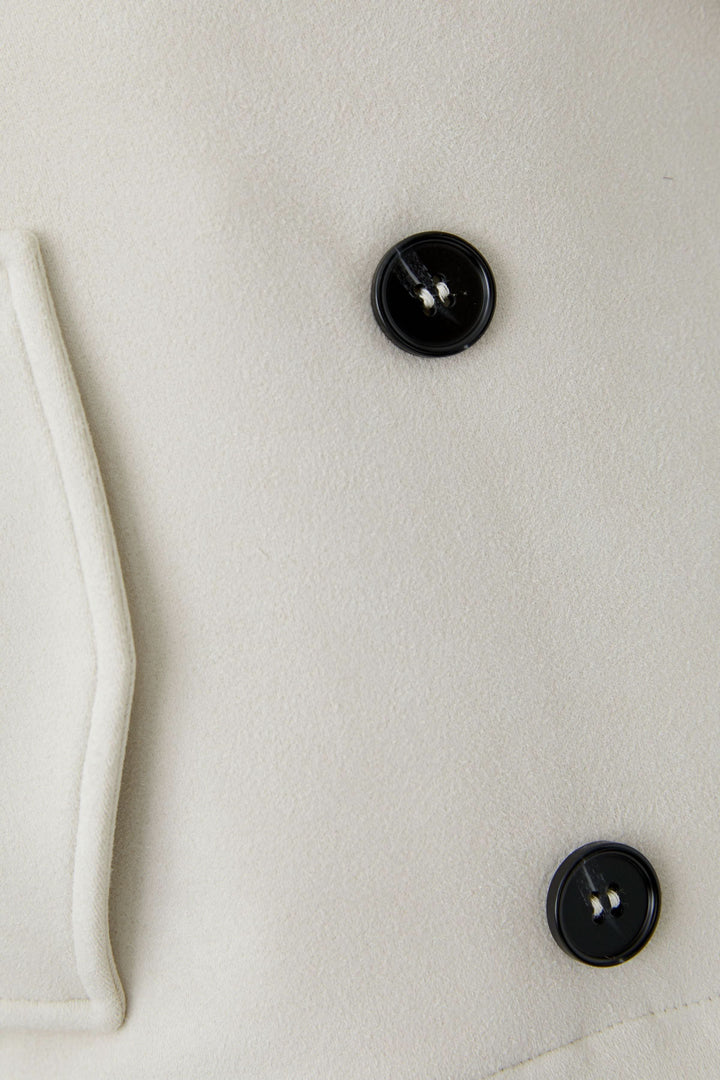 Détail de la Veste courte croisée à col tailleur avec boutons noirs et texture en tissu élégant.