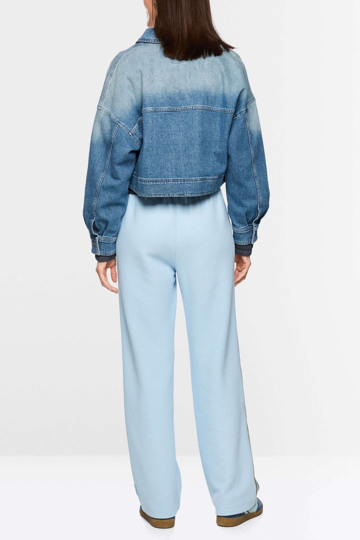 Femme portant une veste courte en jean avec fermeture éclair, design contemporain avec coupe ample et denim souple, vue de dos.