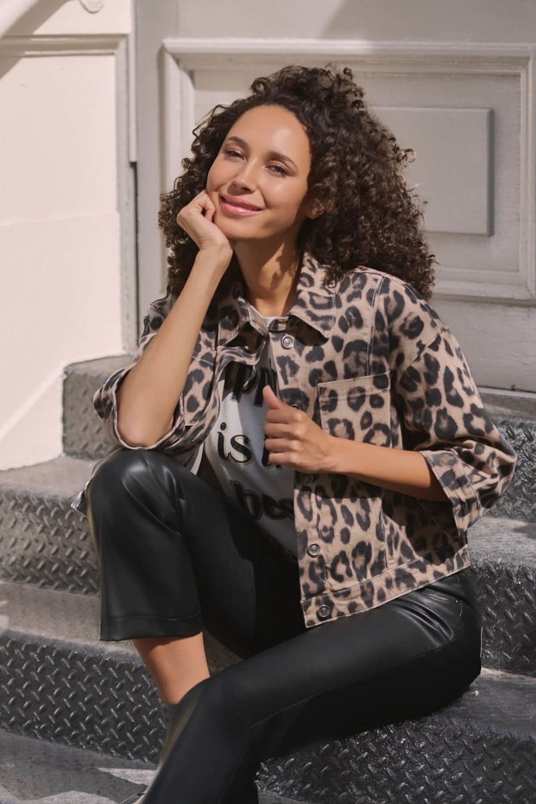 Veste courte à imprimé léopard, look urbain avec pantalon en simili cuir et t-shirt graphique.