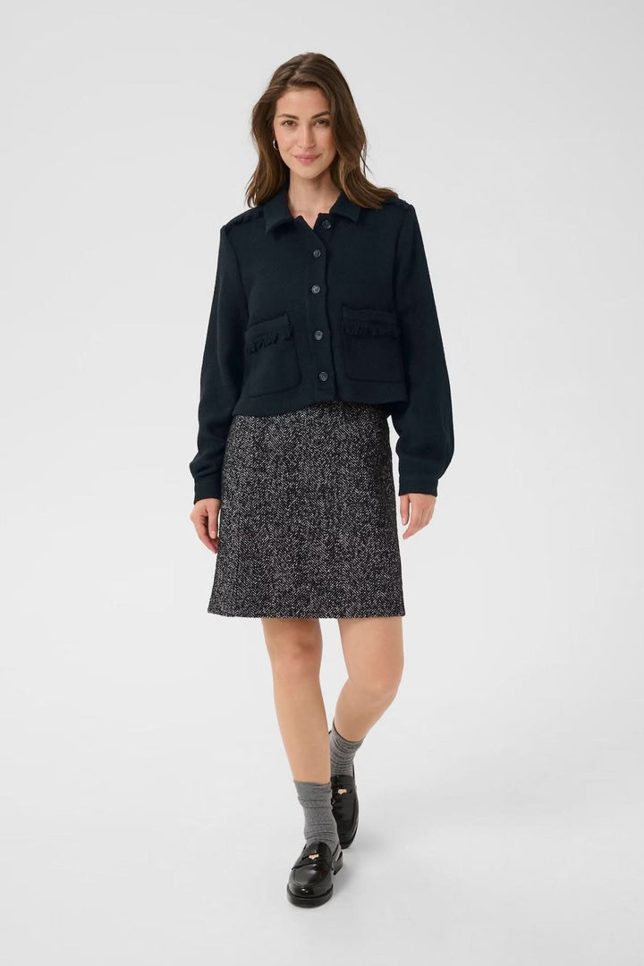 Veste décontractée à col chemise, coupe courte, portée avec une jupe droite pour un look élégant.